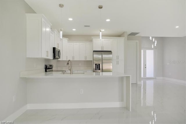 kitchen featuring sink, stainless steel appliances, white cabinets, and pendant lighting