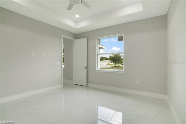 spare room featuring ceiling fan and a raised ceiling