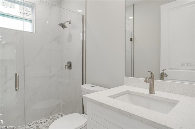 bathroom featuring a shower with shower door, toilet, and vanity