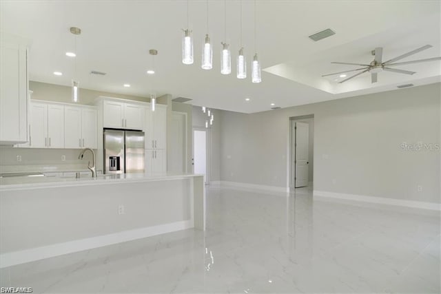 kitchen with pendant lighting, white cabinetry, sink, ceiling fan, and stainless steel refrigerator with ice dispenser