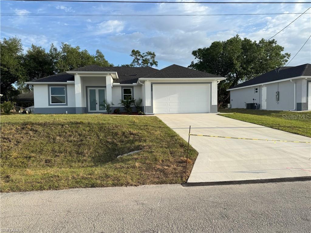 2902 49th St SW, Lehigh Acres, FL 33976 - ranch-style house featuring a front lawn, stucco siding, an attached garage, driveway, and french doors
