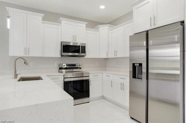 kitchen featuring stainless steel appliances, white cabinetry, sink, and light stone counters