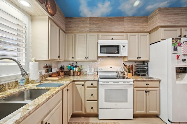 kitchen featuring sink, white appliances, light tile patterned floors, cream cabinets, and light stone countertops