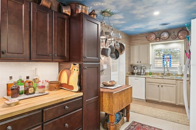 kitchen featuring wood counters, dishwasher, sink, and light tile patterned floors