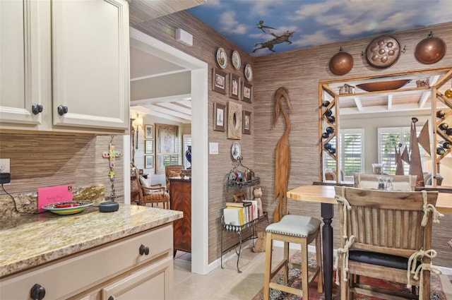 kitchen with tasteful backsplash, light tile patterned floors, light stone counters, and beam ceiling