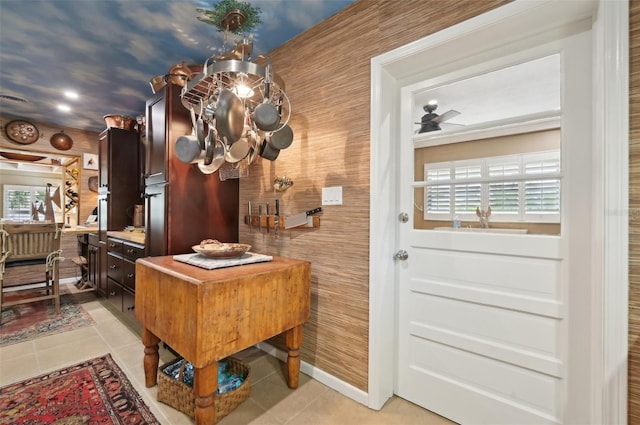 home office with light tile patterned floors and ceiling fan with notable chandelier