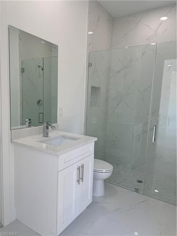 bathroom featuring vanity, a shower with shower door, and toilet