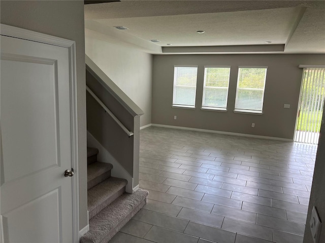 unfurnished room with a textured ceiling and light tile patterned floors