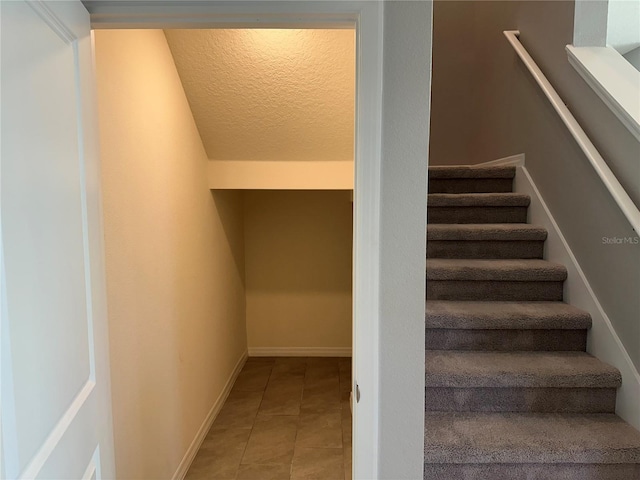 stairs featuring tile patterned flooring and a textured ceiling