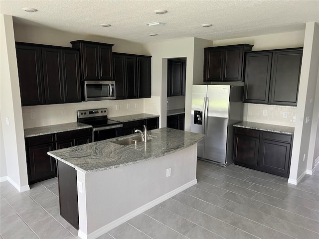 kitchen with tasteful backsplash, appliances with stainless steel finishes, sink, and a center island with sink