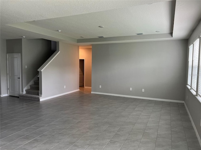 empty room with light tile patterned floors and a tray ceiling