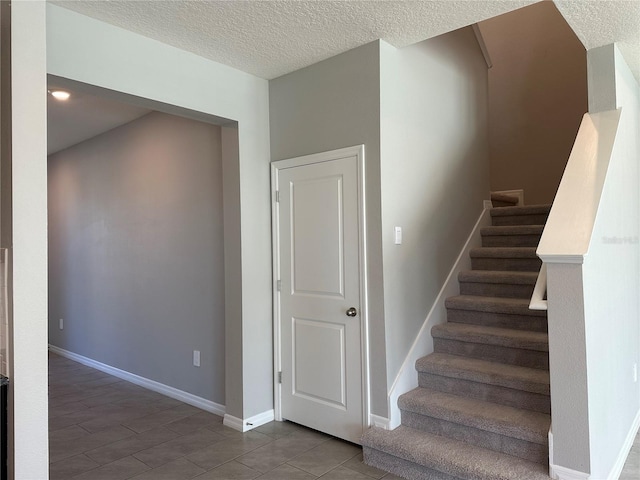 staircase with a textured ceiling and tile patterned floors