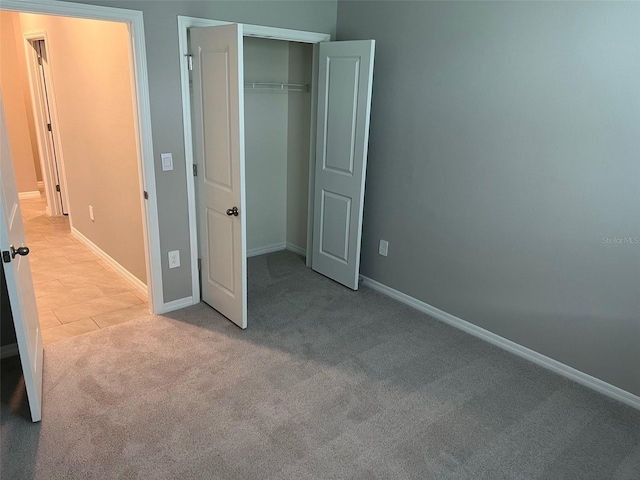 unfurnished bedroom with light colored carpet and a closet