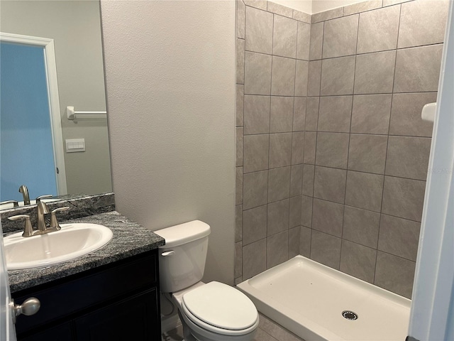 bathroom with toilet, vanity, and a tile shower