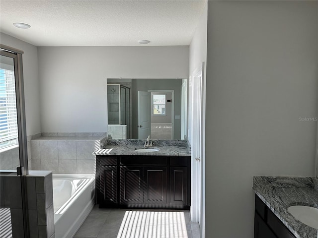 bathroom featuring a textured ceiling, tile patterned flooring, shower with separate bathtub, and vanity