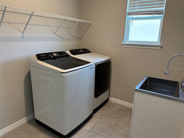 clothes washing area with light tile patterned floors, sink, separate washer and dryer, and cabinets