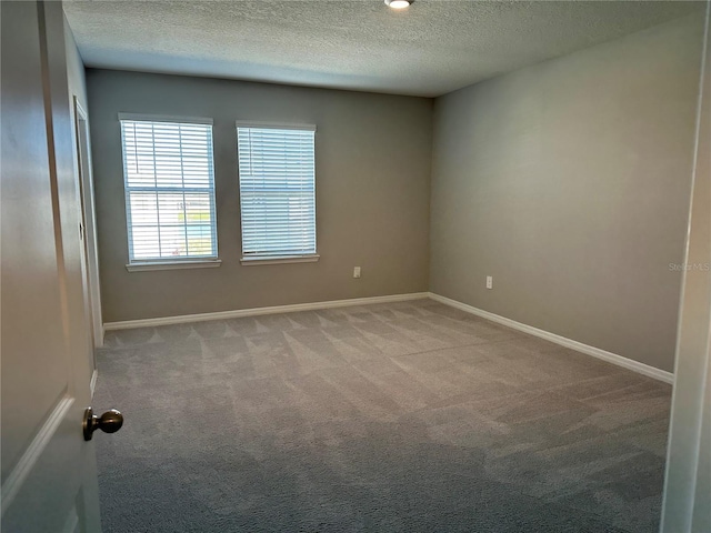 spare room featuring light carpet and a textured ceiling