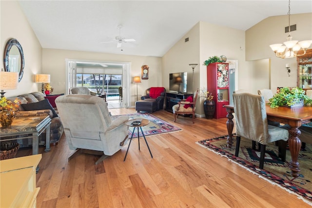 living room featuring vaulted ceiling, ceiling fan with notable chandelier, and light hardwood / wood-style flooring