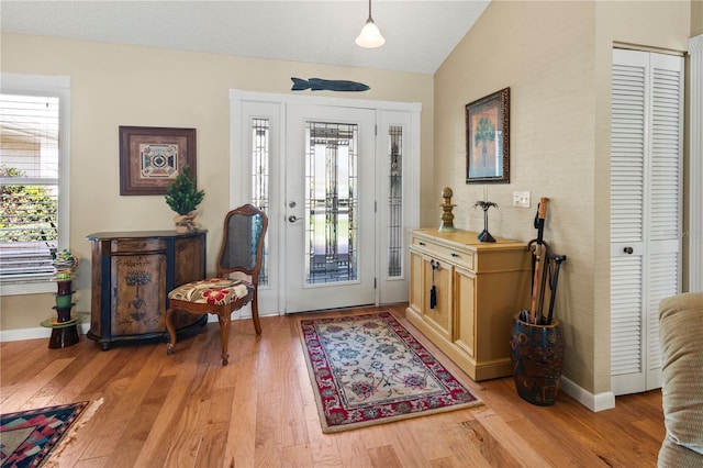 entrance foyer featuring a textured ceiling, lofted ceiling, and light hardwood / wood-style floors