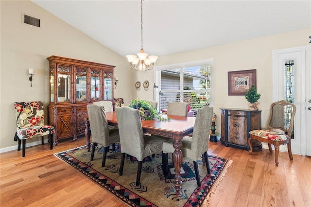 dining area featuring light wood-type flooring, an inviting chandelier, and vaulted ceiling