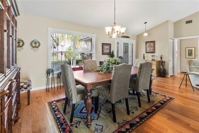 dining space with lofted ceiling, light hardwood / wood-style flooring, and a notable chandelier