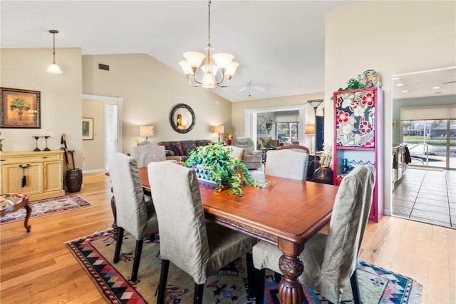 dining room featuring light wood-type flooring, vaulted ceiling, and ceiling fan with notable chandelier