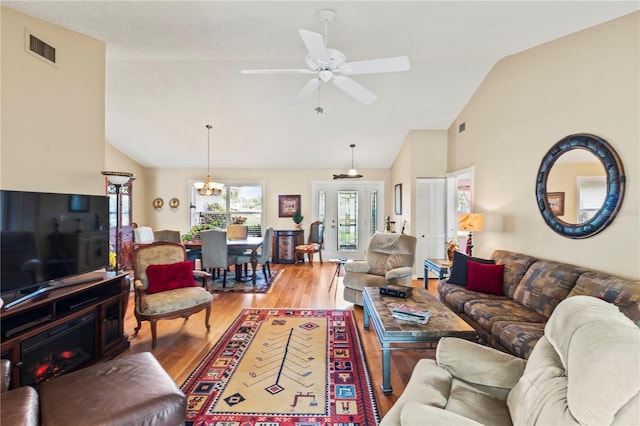 living room featuring vaulted ceiling, ceiling fan with notable chandelier, and wood-type flooring