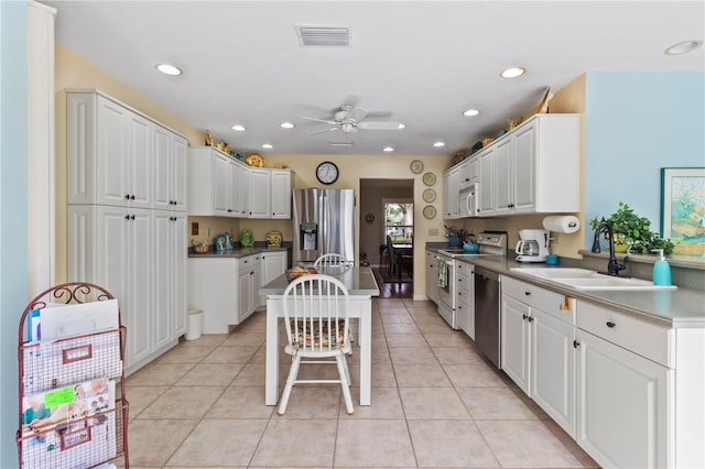 kitchen featuring white cabinetry, stainless steel appliances, sink, light tile patterned flooring, and a breakfast bar area