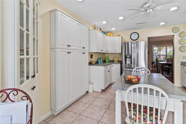 kitchen with ceiling fan, light tile patterned floors, white cabinetry, and stainless steel fridge