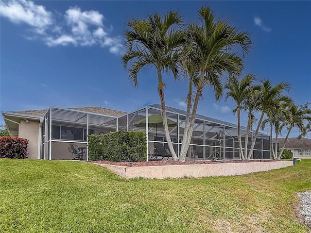 rear view of property with a lawn and glass enclosure