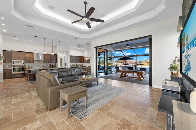 living room with crown molding, a raised ceiling, and ceiling fan