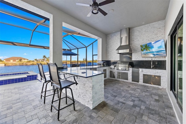 view of patio with a wet bar, a water view, grilling area, glass enclosure, and exterior kitchen