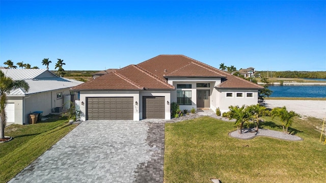 view of front of home with a garage, a front yard, and a water view