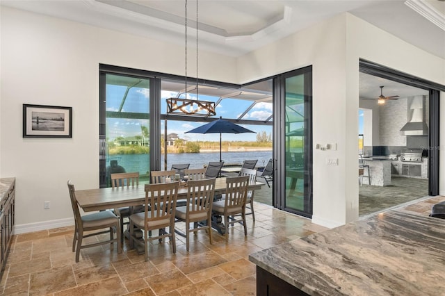 dining room featuring crown molding, a tray ceiling, and a water view