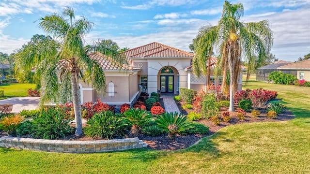 mediterranean / spanish house with a front lawn and french doors