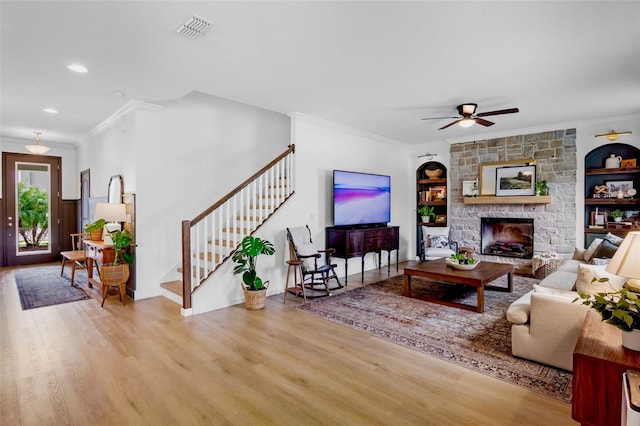 living room with ceiling fan, built in features, ornamental molding, and light hardwood / wood-style flooring