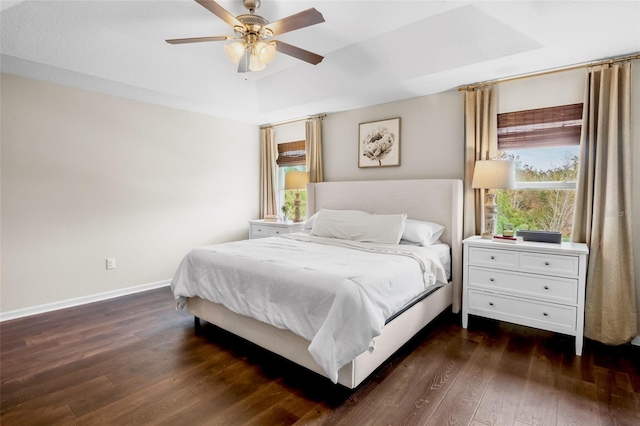 bedroom with ceiling fan, dark hardwood / wood-style flooring, and a raised ceiling