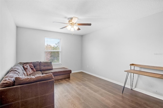 living room with a textured ceiling, ceiling fan, and hardwood / wood-style flooring