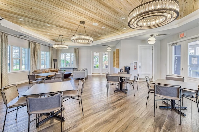 dining area with a notable chandelier, a wealth of natural light, light wood-type flooring, french doors, and wooden ceiling