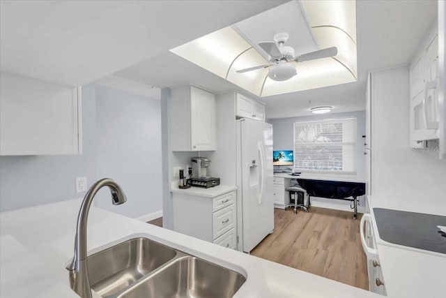 kitchen with sink, white appliances, white cabinets, and light hardwood / wood-style flooring