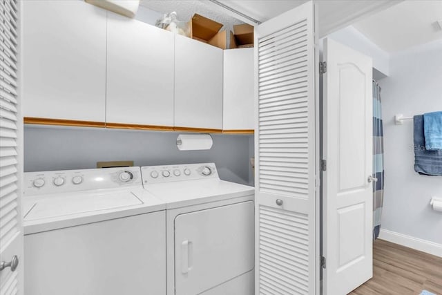 laundry area with light hardwood / wood-style floors, cabinets, and washing machine and dryer