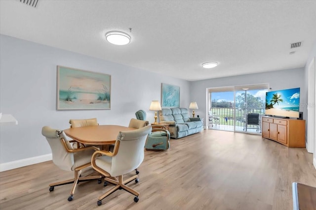 dining area with a textured ceiling and light hardwood / wood-style floors