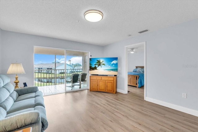 living room with a textured ceiling and light wood-type flooring