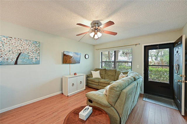 living room with ceiling fan, a textured ceiling, and light hardwood / wood-style flooring