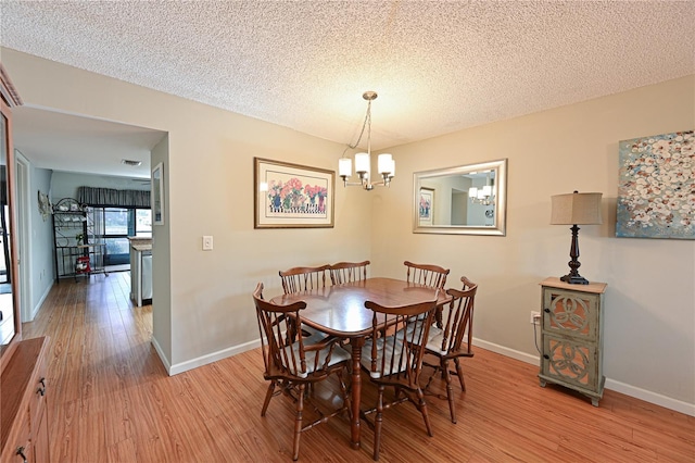 dining room featuring light hardwood / wood-style floors, a textured ceiling, and a chandelier