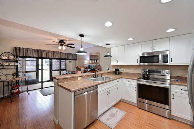 kitchen with sink, white cabinets, appliances with stainless steel finishes, and kitchen peninsula