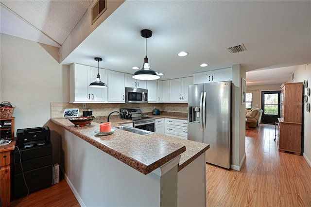 kitchen with white cabinetry, stainless steel appliances, decorative backsplash, and kitchen peninsula