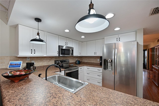 kitchen with white cabinetry, appliances with stainless steel finishes, decorative backsplash, decorative light fixtures, and sink