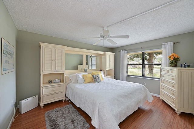 bedroom with a textured ceiling, ceiling fan, and wood-type flooring