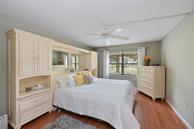 bedroom featuring ceiling fan, dark hardwood / wood-style flooring, and a textured ceiling